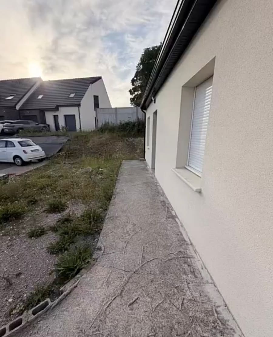 Allée latérale en béton fissuré et terrain en friche avant réfection