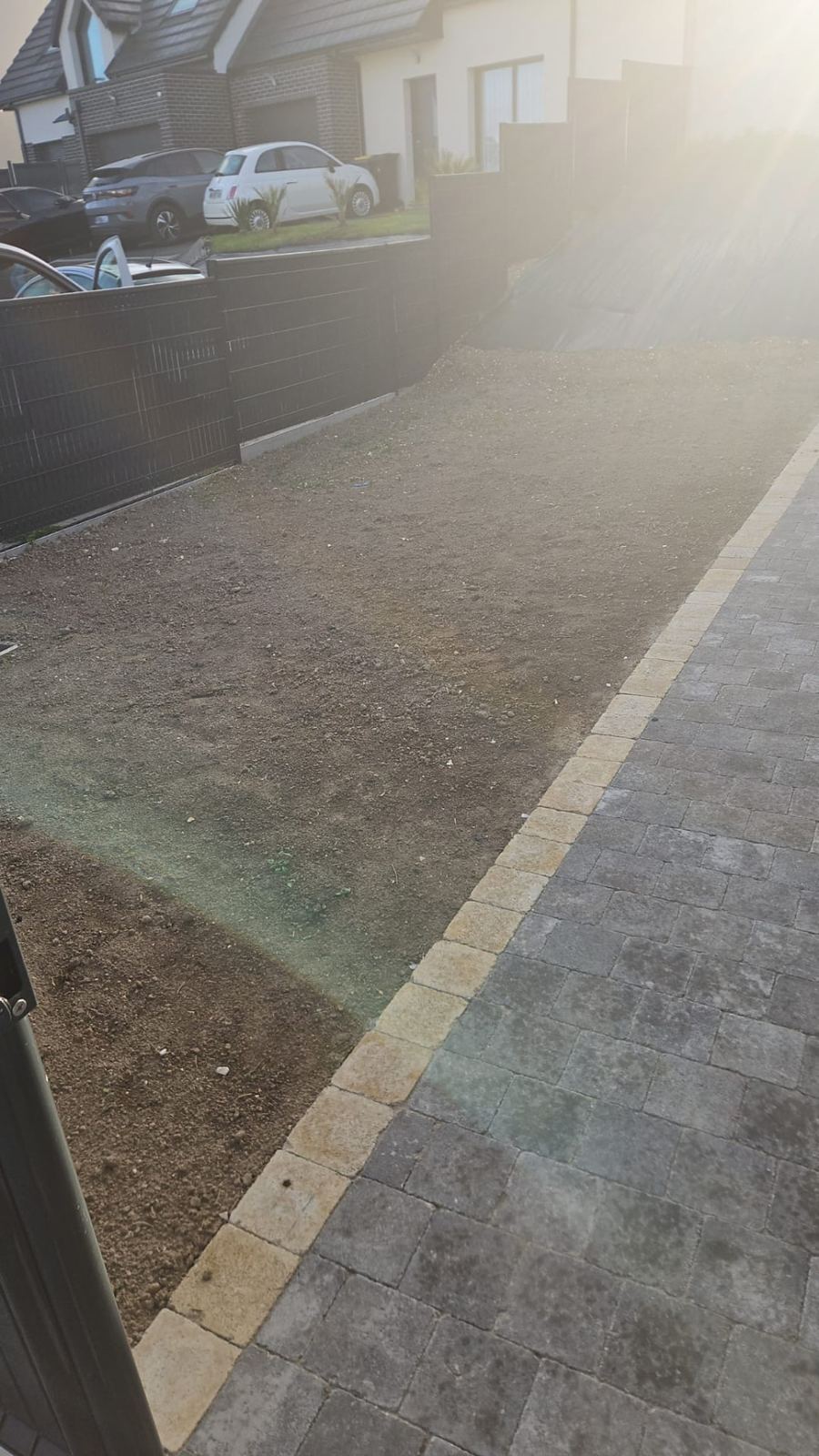 Terrain nu préparé le long de l'allée pavée avant la pose du gazon en rouleaux